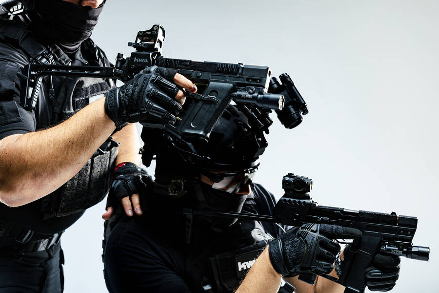 Airsoft player aiming a KWA rifle in studio