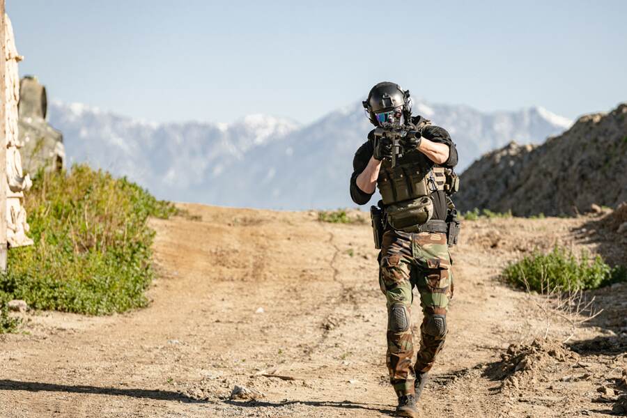 Airsoft player advancing on a mountain trail with KWA rifle